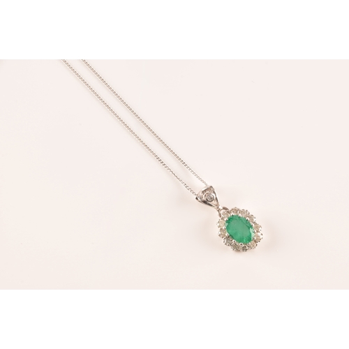 14 - An 18ct white gold emerald and diamond pendant and chain, featuring a oval cut emerald with an appro... 