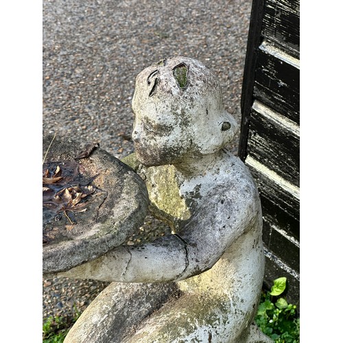 205 - An early 20th century carved and painted stone bird bath, modelled as a nude girl holding aloft a di... 