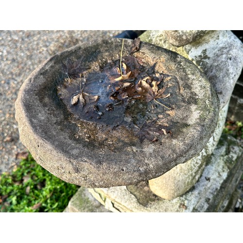 205 - An early 20th century carved and painted stone bird bath, modelled as a nude girl holding aloft a di... 