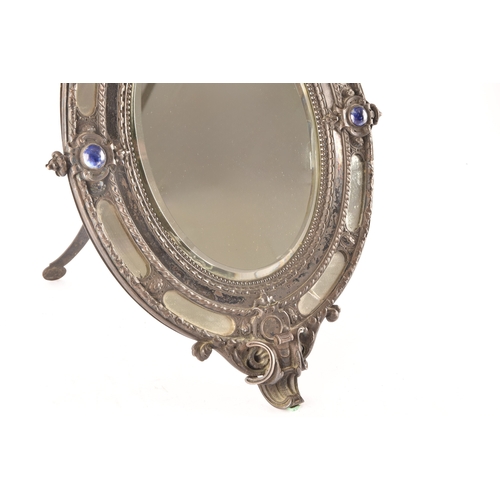 298 - A Victorian metal oval easel mirror, the elaborate frame with scrolled and engraved decoration, with... 