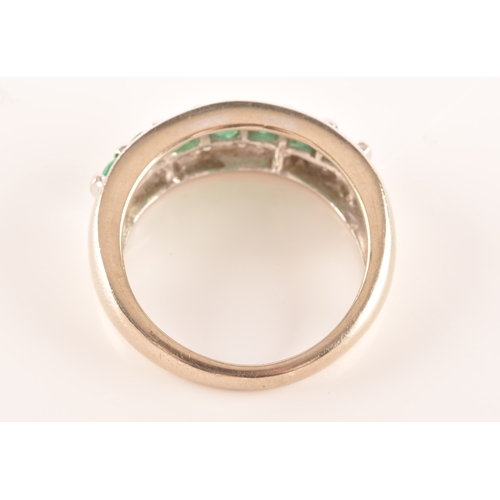 18 - A 14ct white gold ring featuring seven round cut emeralds with a combined approximate weight of 0.35... 