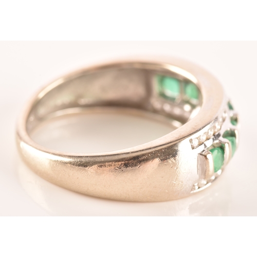 18 - A 14ct white gold ring featuring seven round cut emeralds with a combined approximate weight of 0.35... 