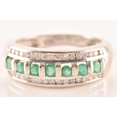 18 - A 14ct white gold ring featuring seven round cut emeralds with a combined approximate weight of 0.35... 