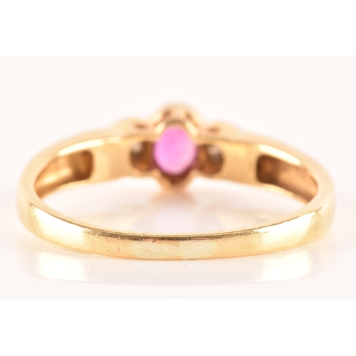 21 - An 18 carat yellow gold ruby and diamond three stone ring, set to centre with a oval ruby with an ap... 