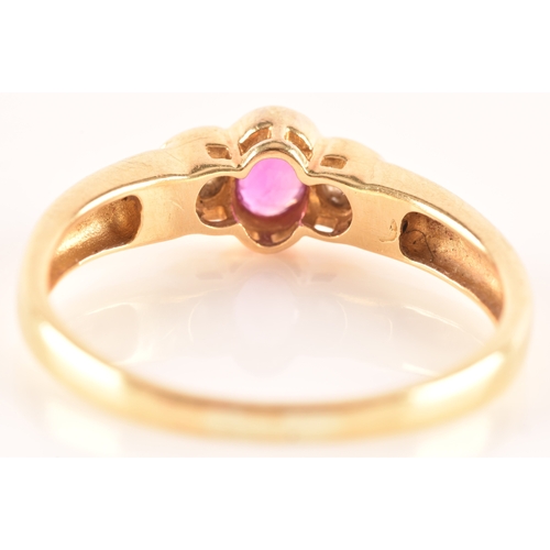 21 - An 18 carat yellow gold ruby and diamond three stone ring, set to centre with a oval ruby with an ap... 