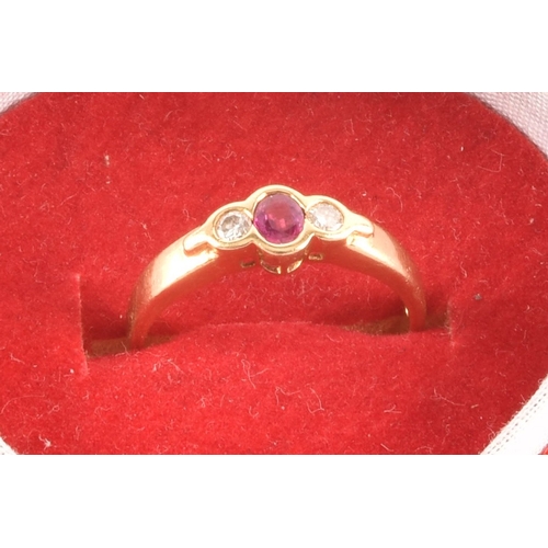 21 - An 18 carat yellow gold ruby and diamond three stone ring, set to centre with a oval ruby with an ap... 