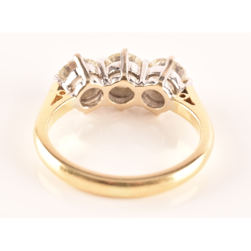 11 - A three stone 18ct yellow and white metal diamond ring, set with three round brilliant cut diamonds ... 