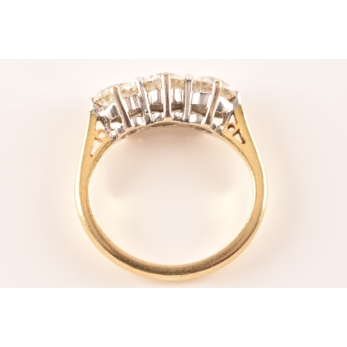 11 - A three stone 18ct yellow and white metal diamond ring, set with three round brilliant cut diamonds ... 