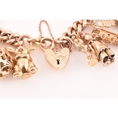 1 - A 9ct rose gold curb link charm bracelet, suspended with a vast collection of 9ct yellow gold charms... 