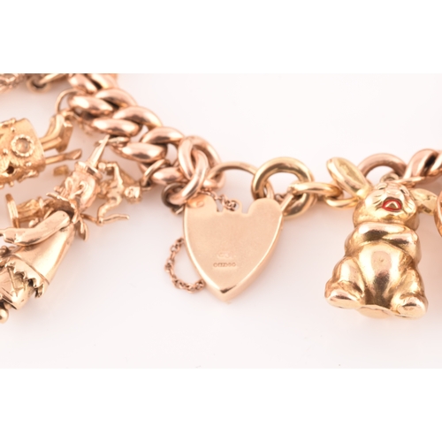 1 - A 9ct rose gold curb link charm bracelet, suspended with a vast collection of 9ct yellow gold charms... 