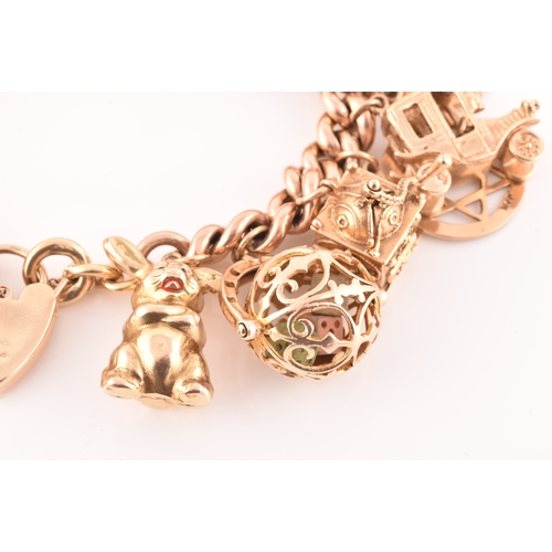 1 - A 9ct rose gold curb link charm bracelet, suspended with a vast collection of 9ct yellow gold charms... 