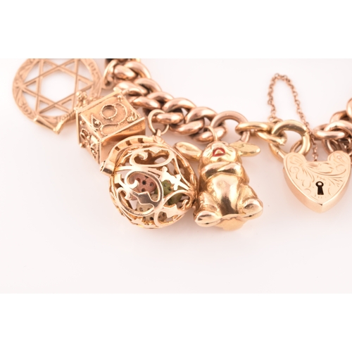 1 - A 9ct rose gold curb link charm bracelet, suspended with a vast collection of 9ct yellow gold charms... 