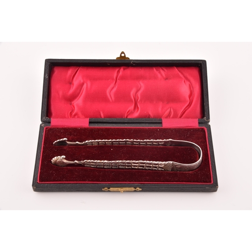 135 - A pair of Georgian cast silver sugar tongs, by Richard Mills, crest engraved, featuring floral  deco... 