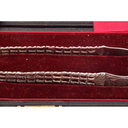 135 - A pair of Georgian cast silver sugar tongs, by Richard Mills, crest engraved, featuring floral  deco... 