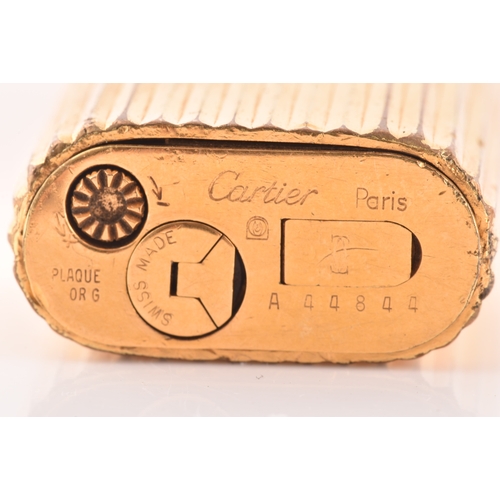 89 - A Cartier gold plated ribbed cigarette lighter, signed Cartier and numbered A44844 to the base, toge... 