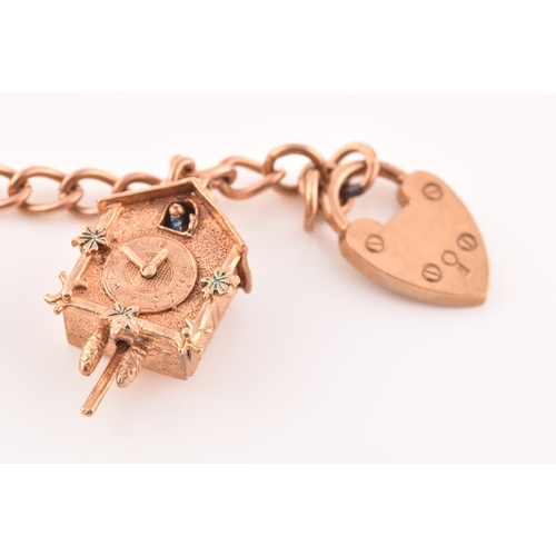 52 - A 9ct rose gold charm bracelet, suspended with three 9ct yellow gold charms, two rose metal charms, ... 