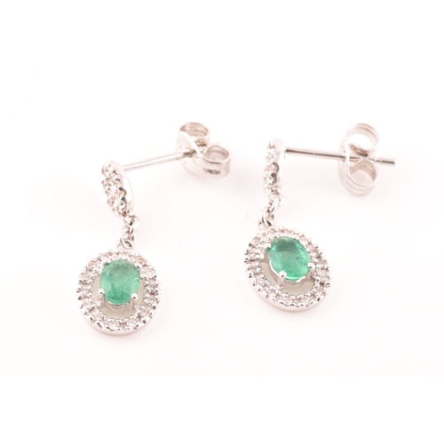 53 - A pair of 18ct white gold emerald and diamond drop earrings, each set with an oval cut emerald with ... 