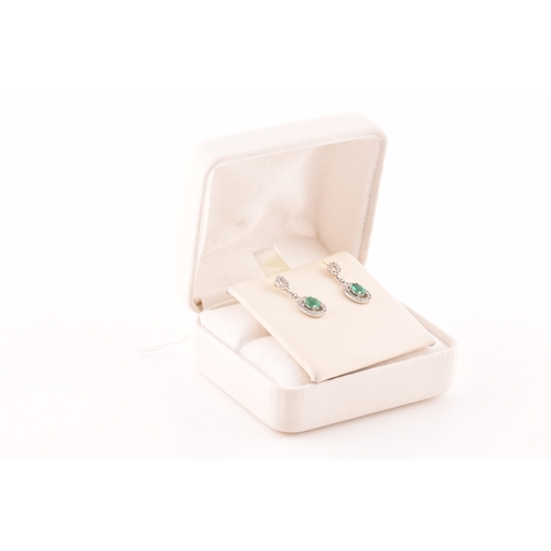 53 - A pair of 18ct white gold emerald and diamond drop earrings, each set with an oval cut emerald with ... 