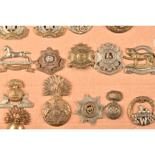 481 - A collection of military cap badges, including The Royal Scots Regiment, The Buffs, The Norfolk Regi... 