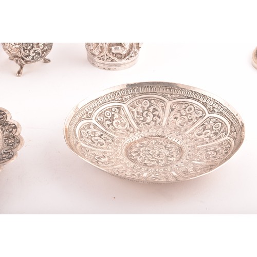 158 - A collection of Burmese white metal objects, including three dishes, a pair of spill vases, a pair o... 