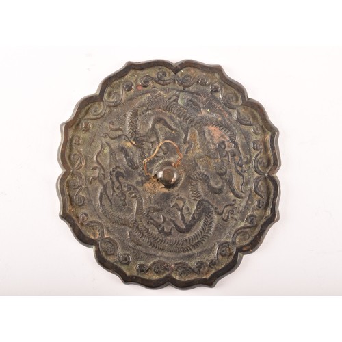 238 - A Chinese bronze hand mirror, decorated with dragon and scrolling motifs within a lotus flower shape... 