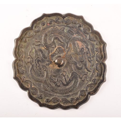 238 - A Chinese bronze hand mirror, decorated with dragon and scrolling motifs within a lotus flower shape... 