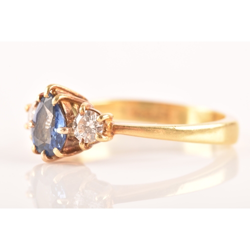 96 - A 18ct yellow gold three stone ring, featuring a pear cut blue stone to the centre, flanked by two r... 