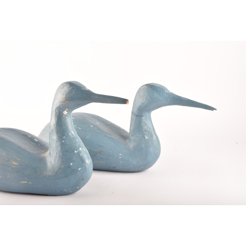 331 - A pair of blue painted carved wooden birds, possibly Grebes, in seated / swimming position.