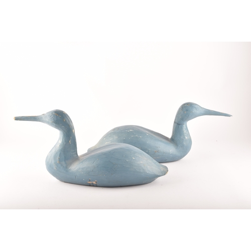 331 - A pair of blue painted carved wooden birds, possibly Grebes, in seated / swimming position.