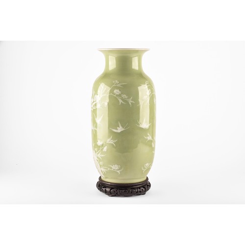 260 - A Chinese green glaze celadon vase with white floral and bird decoration in relief, on a wooden carv... 