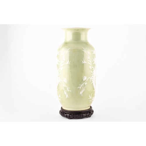 260 - A Chinese green glaze celadon vase with white floral and bird decoration in relief, on a wooden carv... 