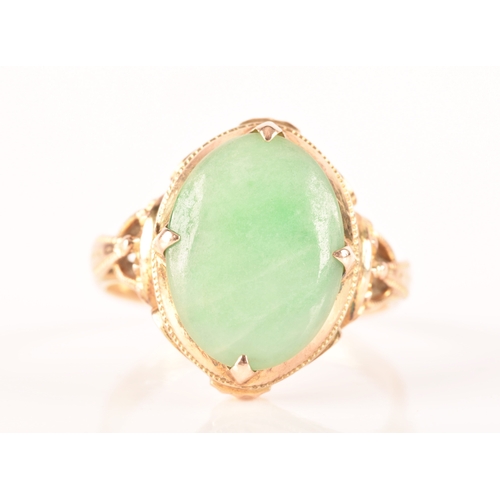 113 - A yellow metal dress ring, set with a cabochon oval jade measuring approximately 14mm length x 10.5m... 