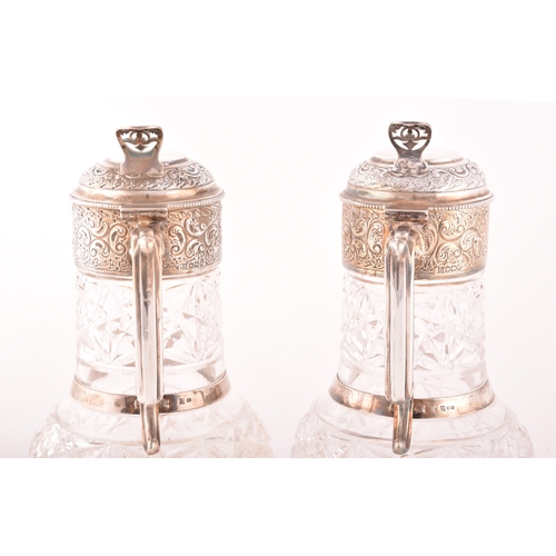 184 - A pair of late Victorian antique silver and crystal claret jugs, ornate foliate decoration, crest en... 