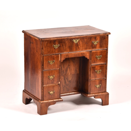 294 - An early 18th century walnut kneehole desk, the oyster veneered walnut cross banded top over a friez... 