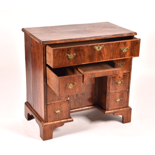 294 - An early 18th century walnut kneehole desk, the oyster veneered walnut cross banded top over a friez... 