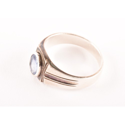 72 - A silver and sapphire gents ring, bezel-set with a mixed oval-cut sapphire, the mount with stylised ... 