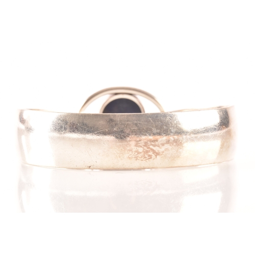 76 - A 1970's Danish sterling silver bangle set with a cabochon blue stone by Niels Erik, diameter 6cm.