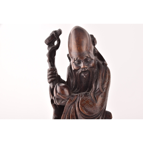 312 - A pair of mid-20th century Chinese carved wood figurines, each depicting an elderly figure holding a... 