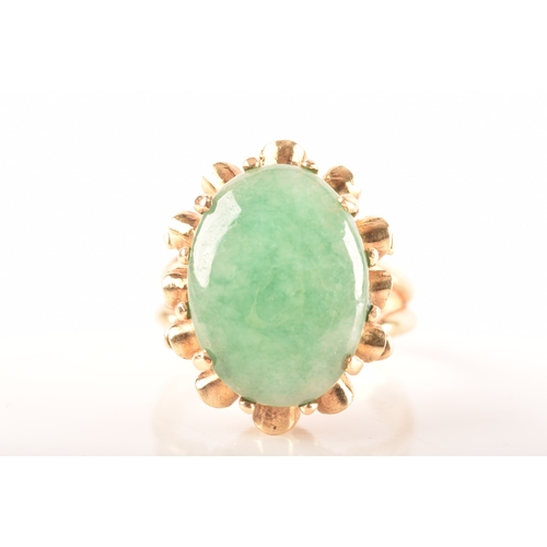 101 - A 9ct gold jadeite ring, set with oval cabochon jadeite measuring approximately 16 x 12mm, in a intr... 