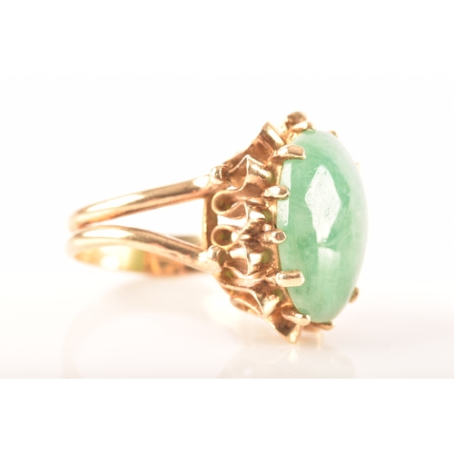 101 - A 9ct gold jadeite ring, set with oval cabochon jadeite measuring approximately 16 x 12mm, in a intr... 