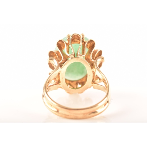 101 - A 9ct gold jadeite ring, set with oval cabochon jadeite measuring approximately 16 x 12mm, in a intr... 