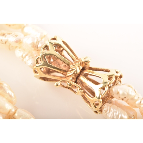 12 - A twisted four strand freshwater pearl necklace, with 14ct yellow gold clasp, 79cm long.