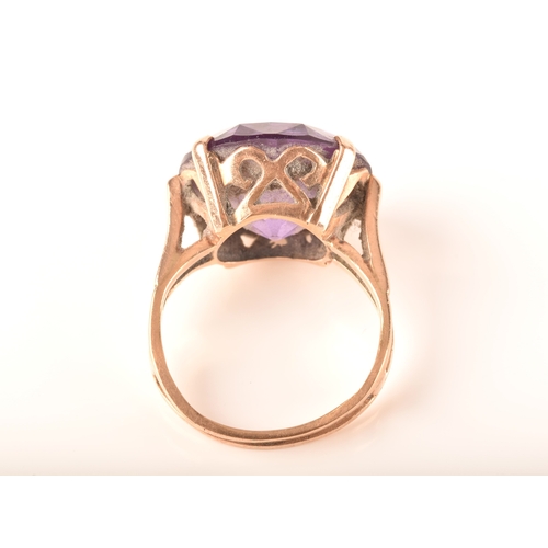 15 - A yellow metal dress ring, set to centre with a round cut synthetic purple sapphire measuring 15mm, ... 