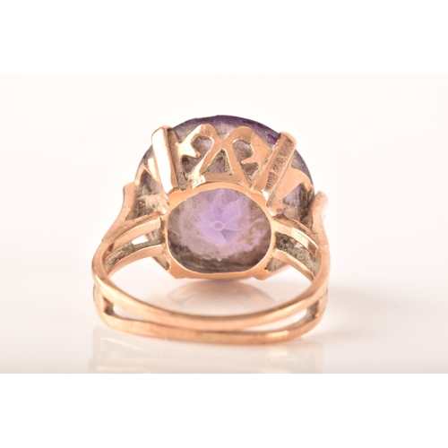 15 - A yellow metal dress ring, set to centre with a round cut synthetic purple sapphire measuring 15mm, ... 