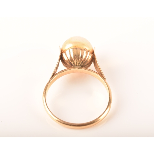 57 - A yellow metal ring, set to centre with a round cultured pearl measuring approximately 8.5mm, with u... 