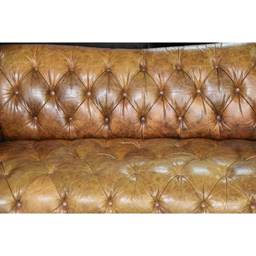 382 - A large brown leather button back Chesterfield style sofa, supported on turned wooden legs, 229 cm w... 