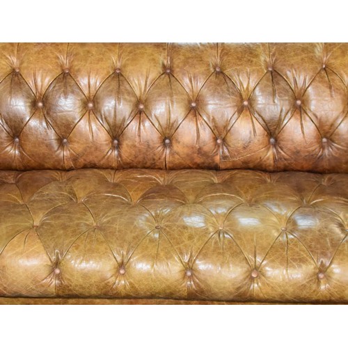 382 - A large brown leather button back Chesterfield style sofa, supported on turned wooden legs, 229 cm w... 