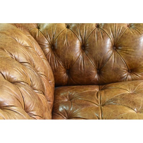 382 - A large brown leather button back Chesterfield style sofa, supported on turned wooden legs, 229 cm w... 