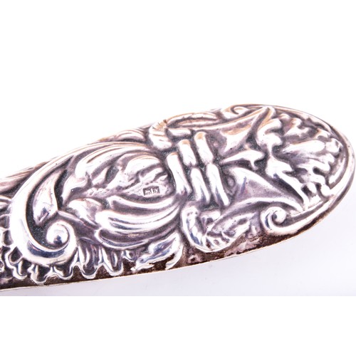 158 - A silver backed hand mirror and hair brush, with repousse decoration featuring leaves, masks, and bi... 