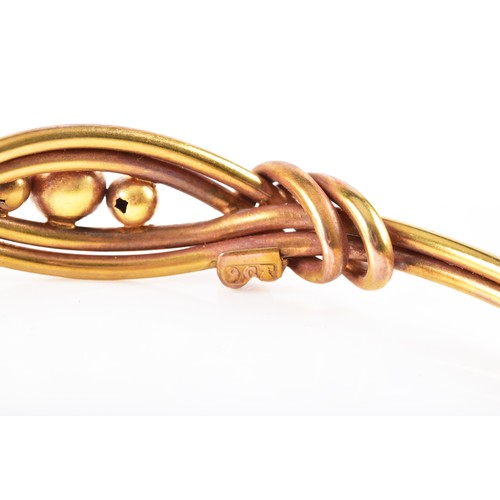 52 - A 9ct bi-colour yellow and rose gold entwined bangle, diameter approximately 5.8 cm, fitted with saf... 